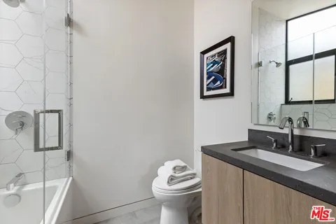 a bathroom with a granite countertop sink mirror vanity and toilet
