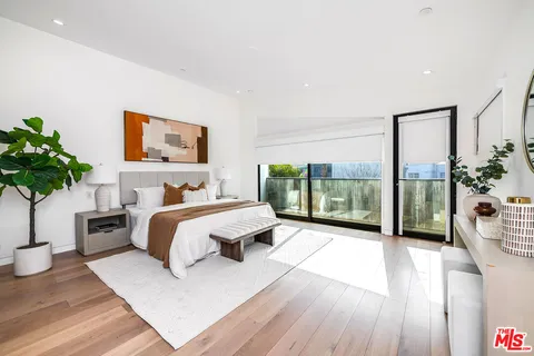 a spacious bedroom with a large bed and a potted plant