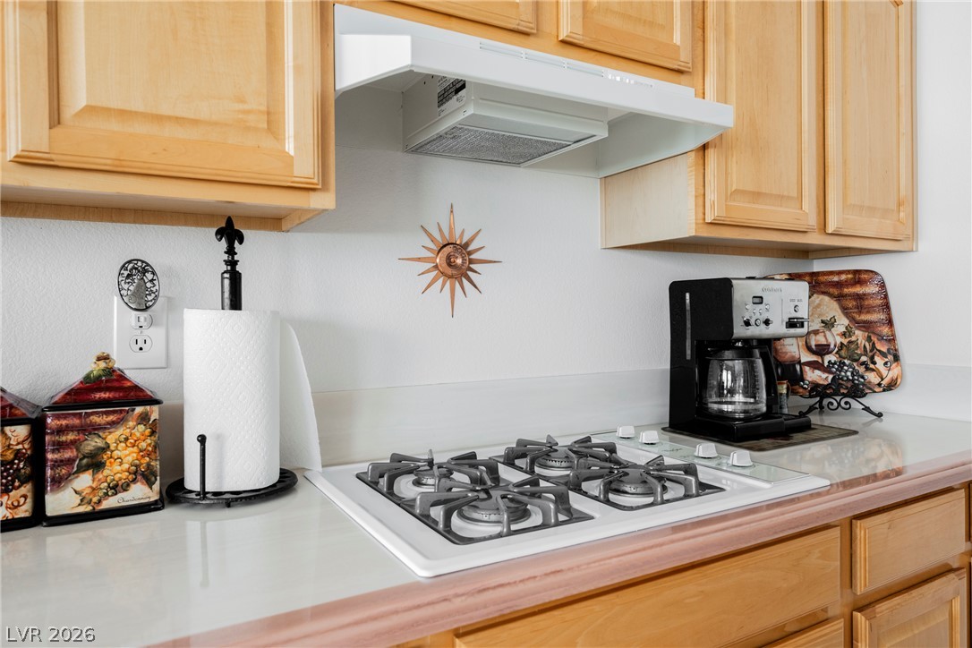 5494 Pine Ranch Street Las Vegas, NV 89113 - Photo 35 of 54 A well-appointed kitchen features a modern gas cooktop integrated into a light-colored countertop.