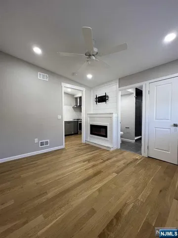 an empty room with wooden floor fireplace and windows