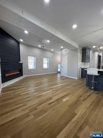 a view of an empty room with kitchen and window