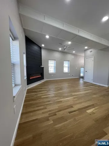 a view of an empty room with wooden floor and staircase