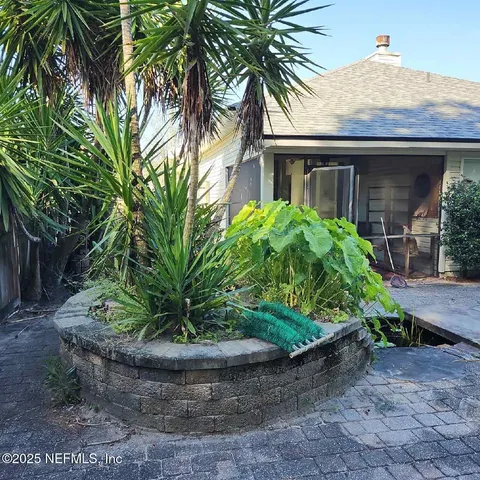 a view of a house with a yard and potted plants
