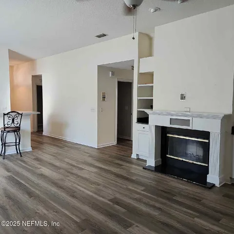 a view of an empty room with wooden floor fireplace and a window