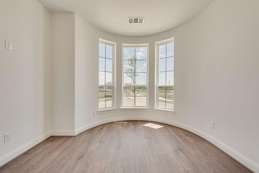 248 Golden Run Drive Fate, TX 75189 - Photo 11 of 34 an empty room with wooden floor and windows