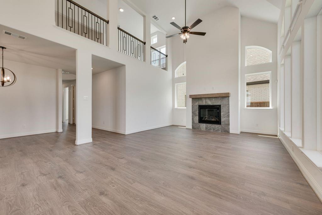 248 Golden Run Drive Fate, TX 75189 - Photo 6 of 34 an empty room with wooden floor fireplace and windows