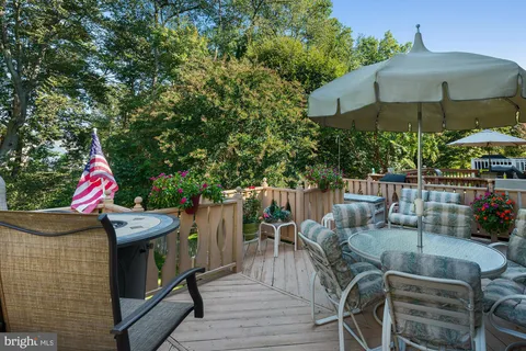 a view of a patio with couches table and chairs under an umbrella with a barbeque