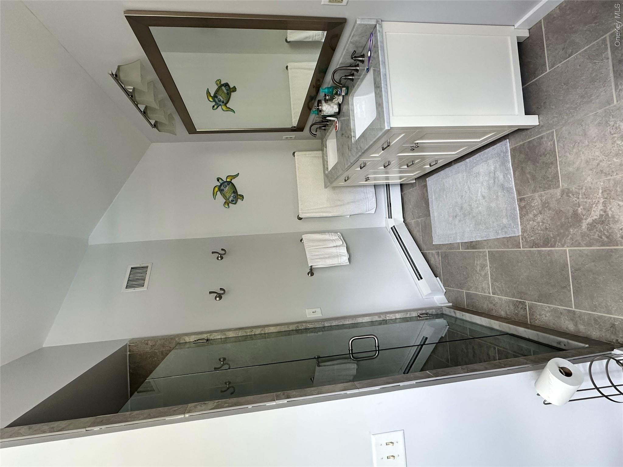95 Weed Road Pine Bush, NY 12566 - Photo 14 of 31 Bathroom featuring a large glass-enclosed shower with tile surround, a double vanity with undermount sinks and a stone countertop, a framed mirror, and large format floor tiling