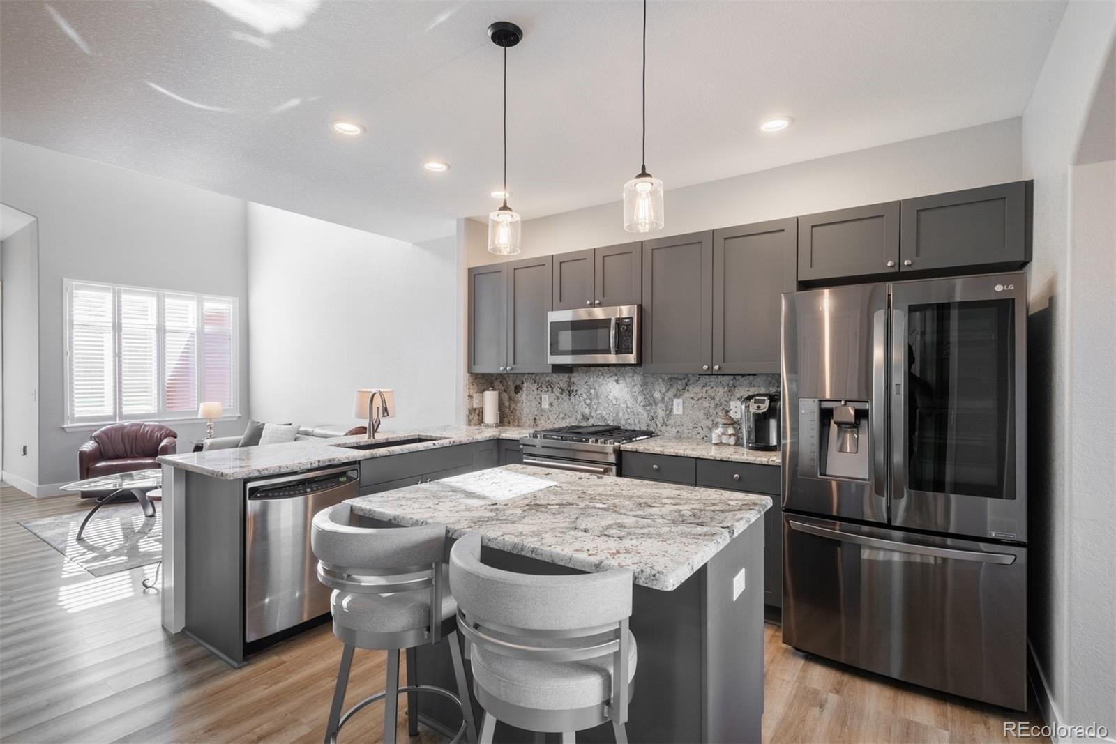 8555 Gold Peak Drive, Unit B Highlands Ranch, CO 80130 - Photo 6 of 38 a kitchen with stainless steel appliances granite countertop a table chairs stove refrigerator and microwave