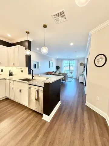 a kitchen with stainless steel appliances granite countertop a sink a stove and a wooden floors