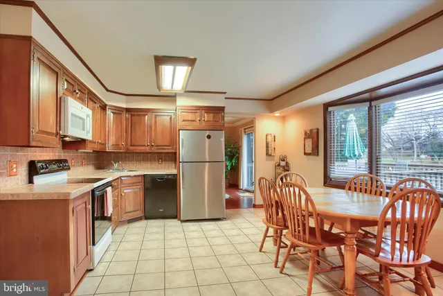 a kitchen with stainless steel appliances granite countertop a refrigerator a stove a sink dishwasher with a dining table and chairs