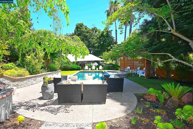 a view of a patio with couches table and chairs under an umbrella