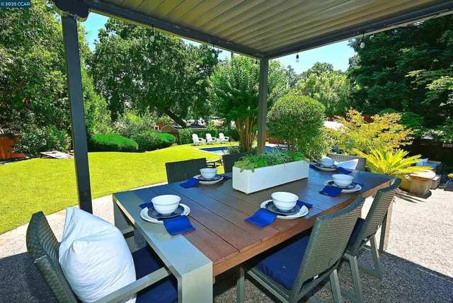 a view of a house with a big yard potted plants and large tree