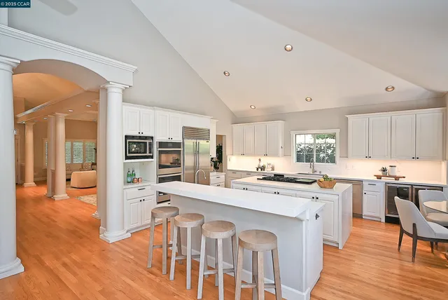 a kitchen with stainless steel appliances kitchen island granite countertop a stove top oven a sink a refrigerator and cabinets