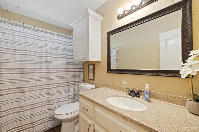 a bathroom with a granite countertop toilet sink and mirror