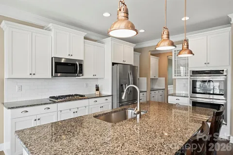 a kitchen with stainless steel appliances kitchen island granite countertop a stove a sink and a microwave