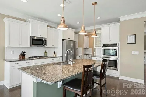 a kitchen with kitchen island granite countertop a table chairs microwave and cabinets