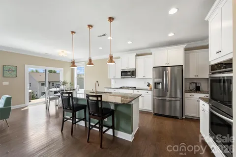 a kitchen with stainless steel appliances granite countertop a table chairs stove and refrigerator
