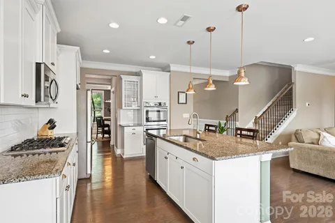 a kitchen with stainless steel appliances granite countertop a sink a stove and a wooden floors