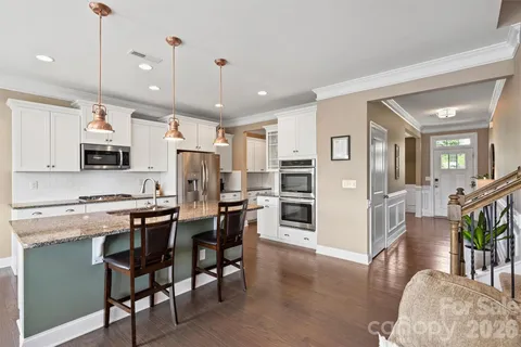 a kitchen with stainless steel appliances kitchen island granite countertop a table chairs and a refrigerator