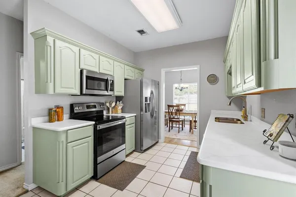 a view of a kitchen with a sink and dishwasher a refrigerator with white cabinets