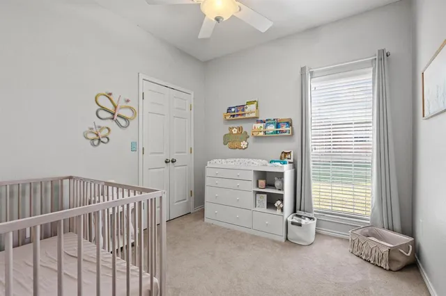 a view of a bedroom with baby crib and a window