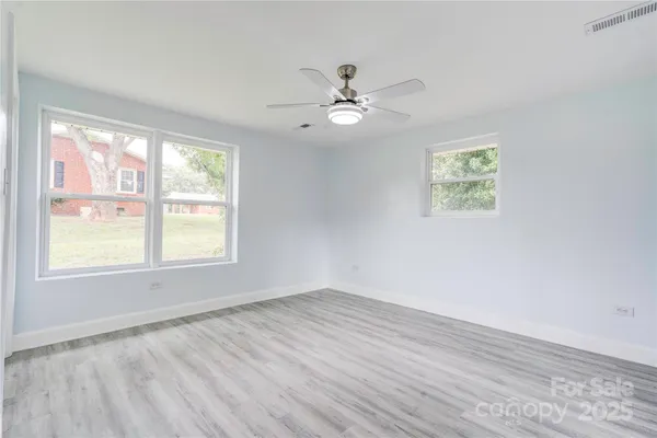 a view of empty room with wooden floor and fan