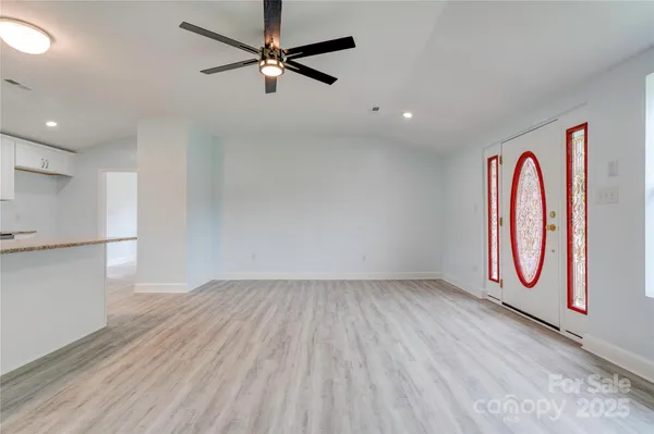 an empty room with wooden floor fan and windows