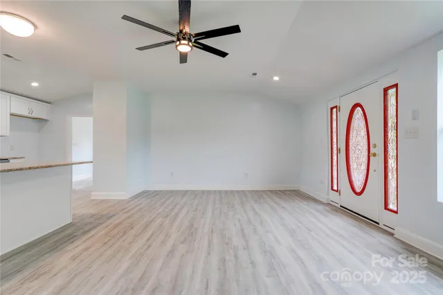 an empty room with wooden floor fan and windows