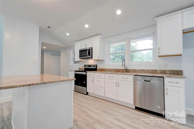 a kitchen with granite countertop cabinets stainless steel appliances a sink and a window
