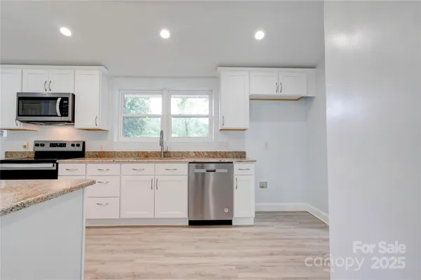 a kitchen with stainless steel appliances granite countertop a stove a sink and a microwave