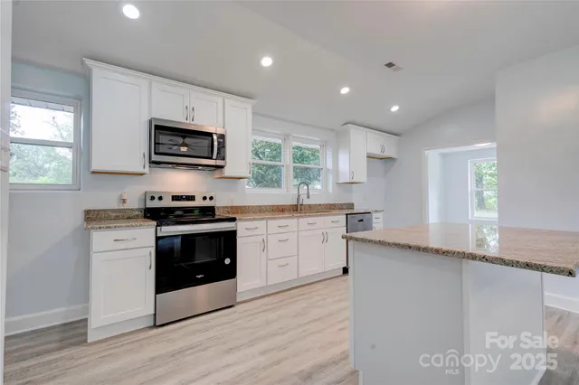 a kitchen with stainless steel appliances granite countertop a stove a sink and a microwave