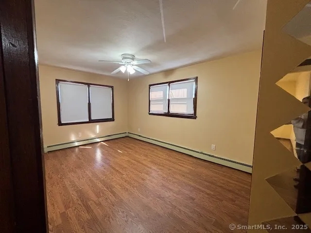 a view of empty room with wooden floor and fan