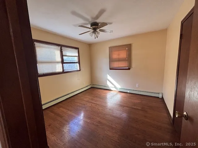 an empty room with wooden floor fan and windows