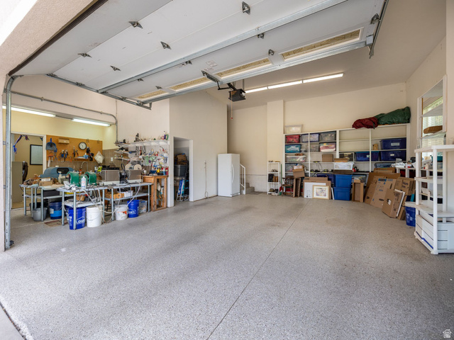 1317 South Pond Circle Mapleton, UT 84664 - Photo 54 of 63 Spacious garage featuring a durable epoxy floor, ample overhead fluorescent lighting, and a dedicated workbench area