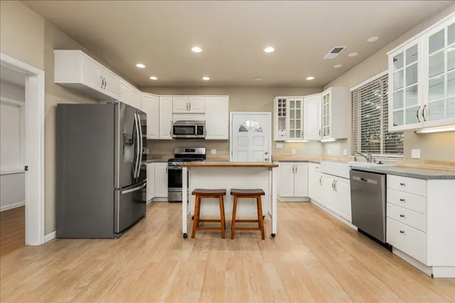 a kitchen with a refrigerator a sink and white cabinets