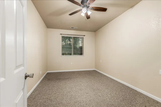 an empty room with a window and a ceiling fan