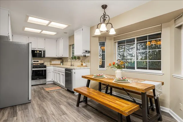 a kitchen with a refrigerator a sink dishwasher a stove and a dining table with wooden floor