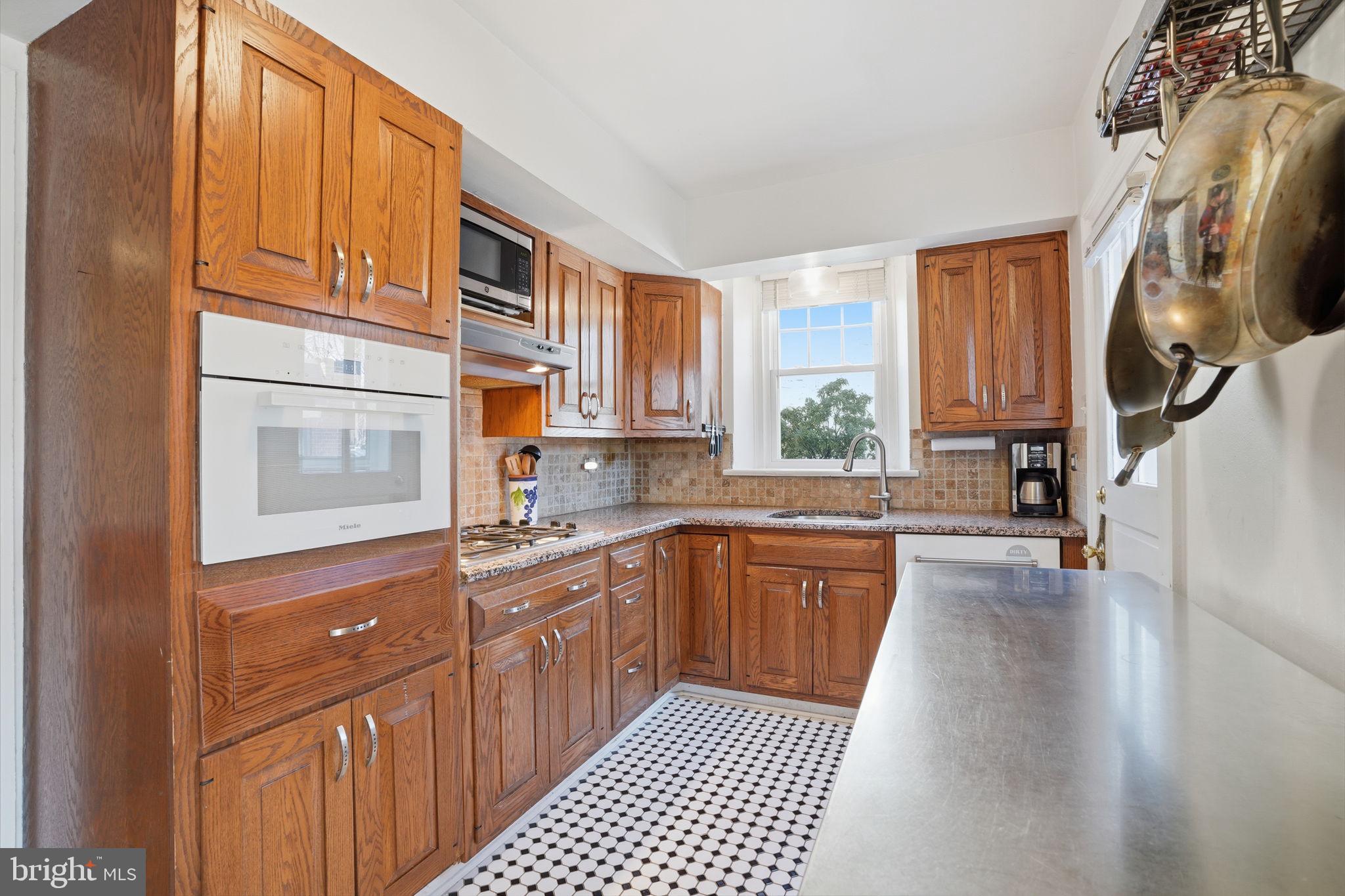 7791 Spring Avenue Elkins Park, PA 19027 - Photo 7 of 33 a kitchen with stainless steel appliances granite countertop a stove a sink and a microwave