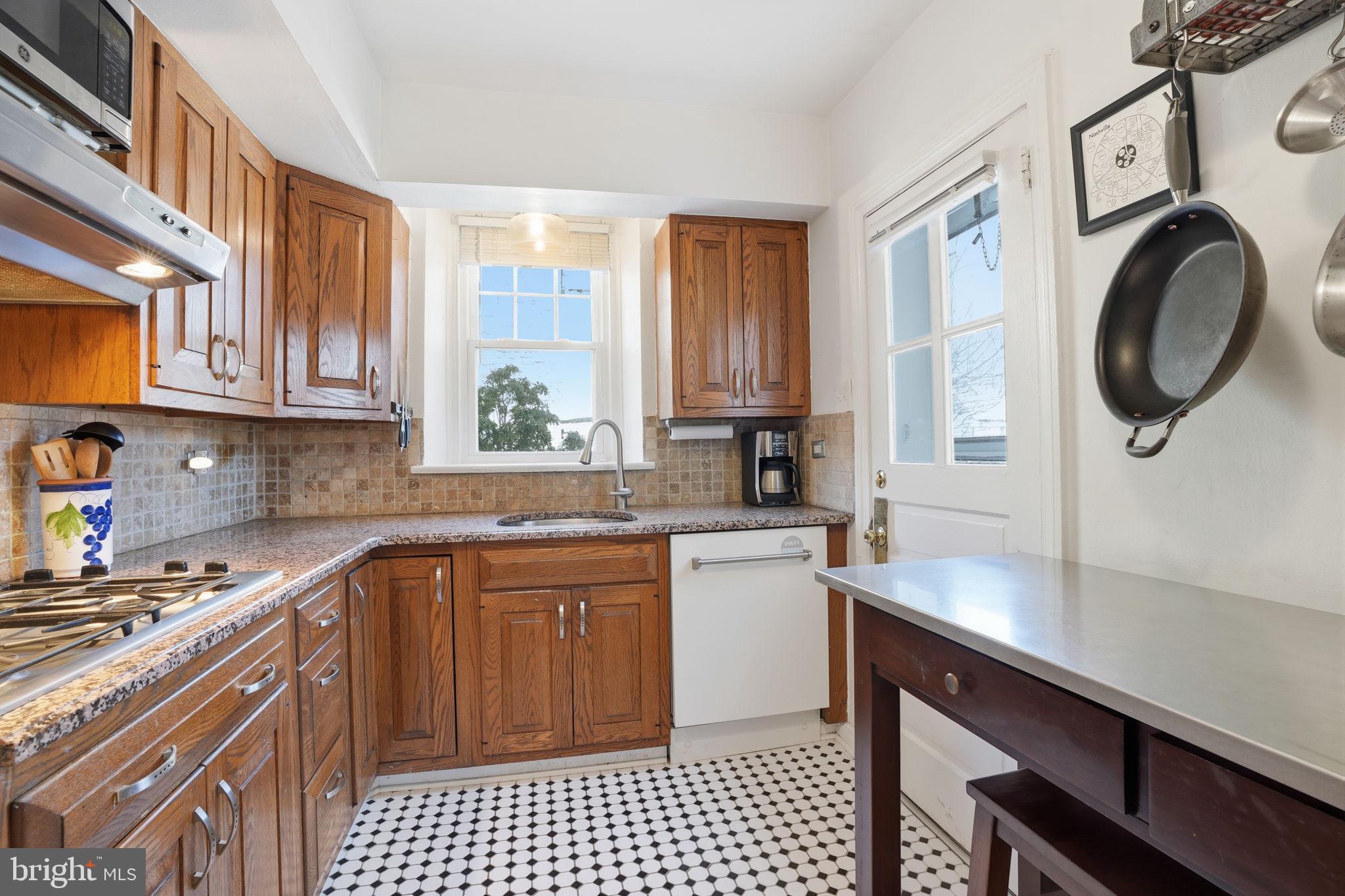 7791 Spring Avenue Elkins Park, PA 19027 - Photo 8 of 33 a kitchen with stainless steel appliances granite countertop a sink a stove a refrigerator cabinets and a window