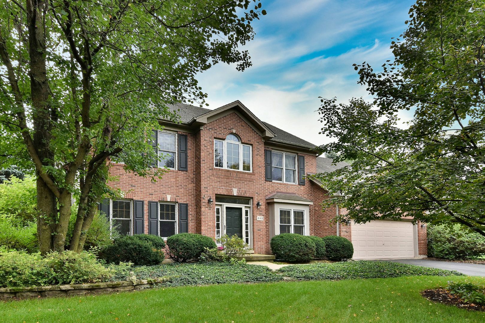 a front view of a house with a yard and trees