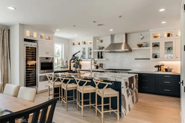 a kitchen with stainless steel appliances granite countertop a stove top oven a sink a dining table and chairs