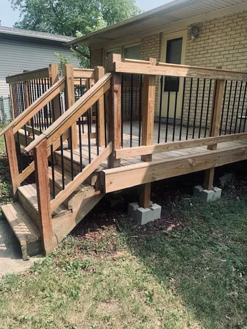 a view of a house with a small yard and wooden deck