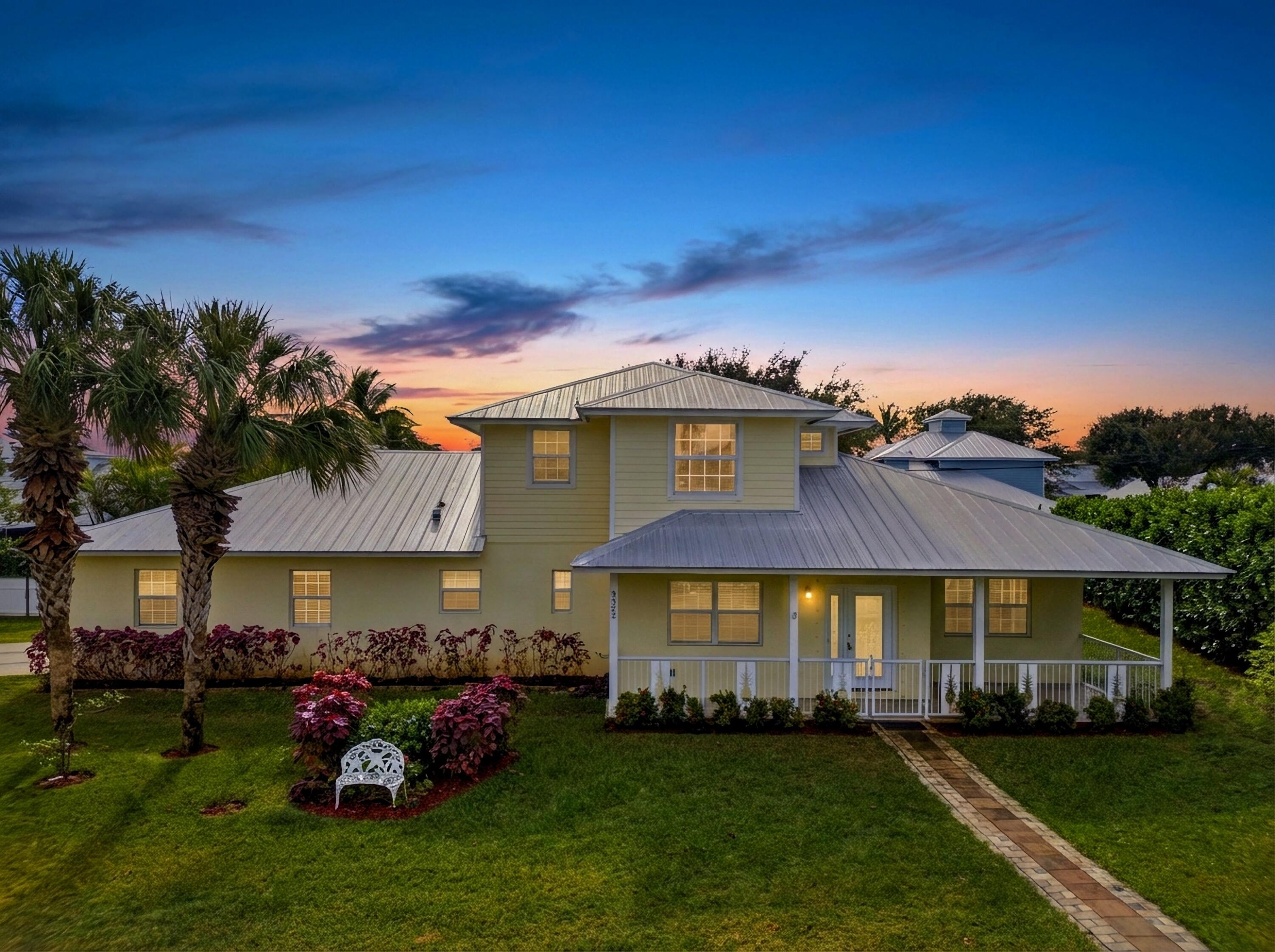 9322 Southeast Athena Street Hobe Sound, FL 33455 - Photo 2 of 69 a front view of a house with a garden