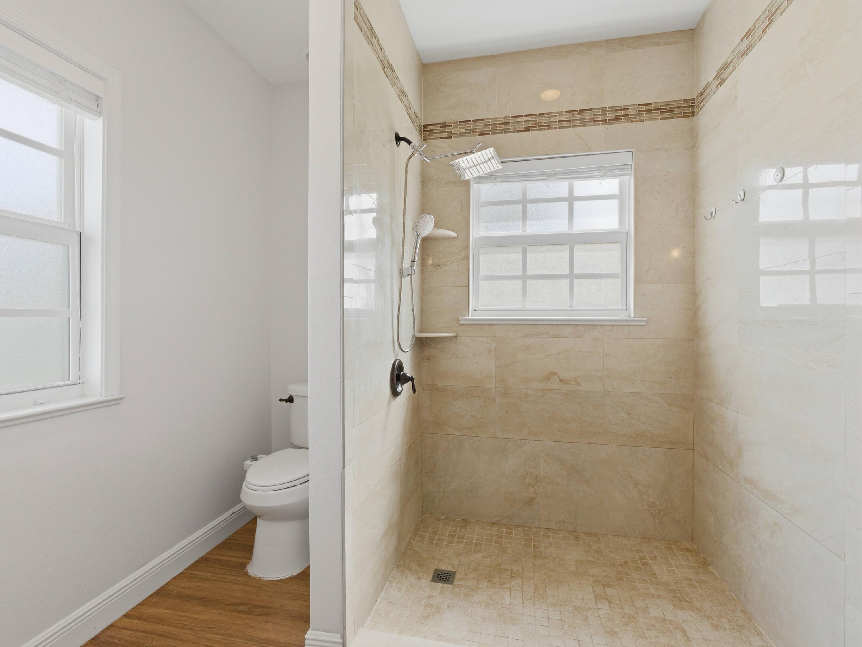 9322 Southeast Athena Street Hobe Sound, FL 33455 - Photo 37 of 69 a bathroom with a granite countertop shower a toilet and a window