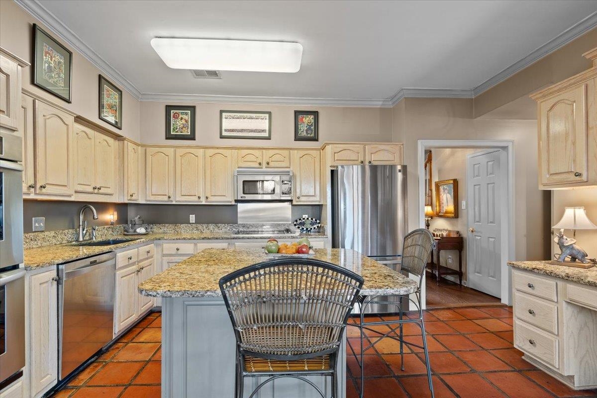 732 North Tree Drive Collierville, TN 38017 - Photo 16 of 40 Kitchen featuring crown molding, stainless steel appliances, light stone countertops, a center island, and a kitchen breakfast bar