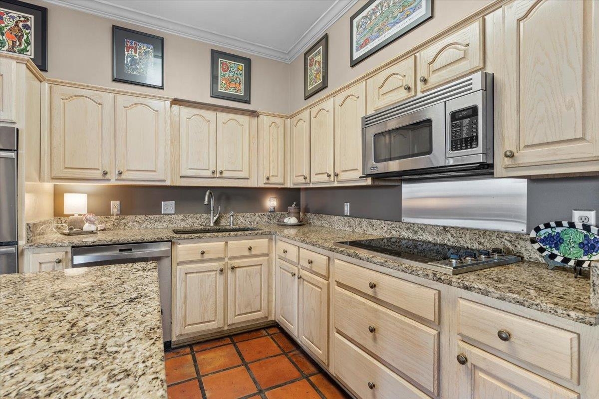 732 North Tree Drive Collierville, TN 38017 - Photo 18 of 40 Kitchen with appliances with stainless steel finishes, ornamental molding, light stone countertops, dark tile patterned floors, and light brown cabinetry