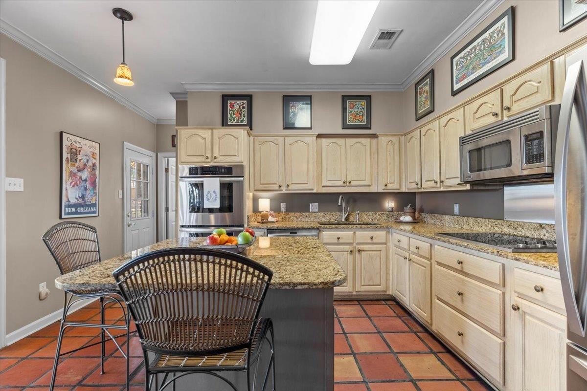 732 North Tree Drive Collierville, TN 38017 - Photo 19 of 40 Kitchen featuring appliances with stainless steel finishes, ornamental molding, a kitchen breakfast bar, pendant lighting, and light stone countertops