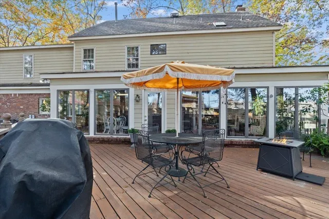 a view of a patio with table and chairs under an umbrella with a barbeque