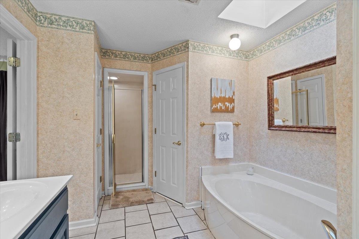 732 North Tree Drive Collierville, TN 38017 - Photo 26 of 40 Full bathroom with vanity, light tile patterned floors, wallpapered walls, a textured ceiling, and a garden tub
